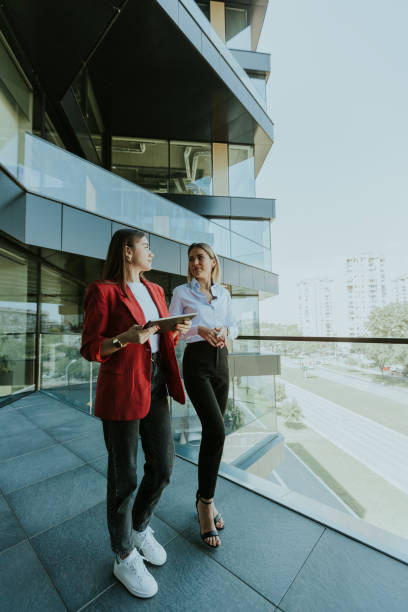 istock Two businesswomen discuss strategy outside modern office building in daylight 2153789846