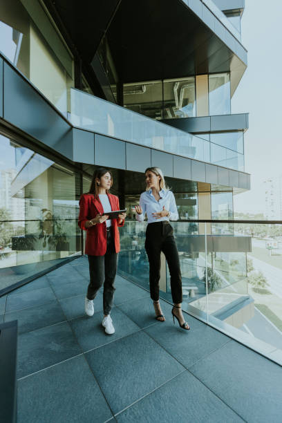 istock Two businesswomen discuss strategy outside modern office building in daylight 2153789849