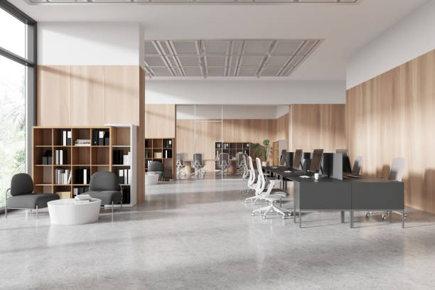 istock Modern office interior with desks, chairs, computers, and bookshelves, on a concrete floor and wooden panel background, concept of workplace. 3D Rendering 2153791249
