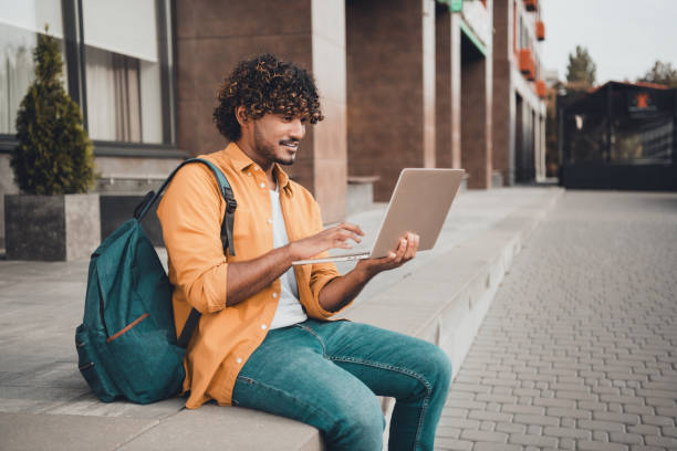istock Photo of confident clever young man it specialist sitting working using modern device wireless device connection autumn day outdoor 2153798250
