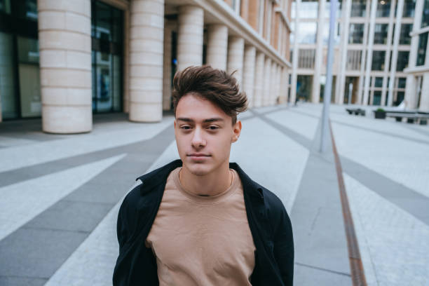 istock young man in a beige shirt and black jacket walks confidently through a modern urban setting with large pillars, looking straight ahead 2153799226