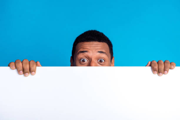 istock Photo of nice young man hide face behind empty space blank isolated on blue color background 2153800103