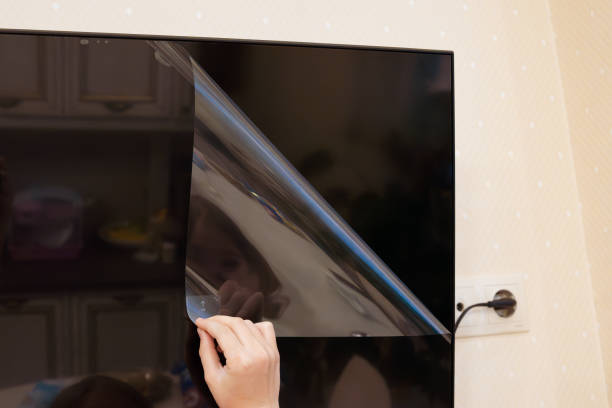 istock hand removes protective film from new tv screen 2153802006