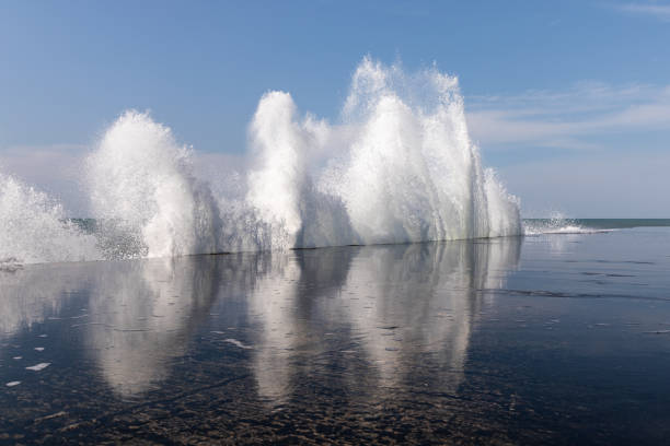 Crashing sea waves on the promenade, with water reflection