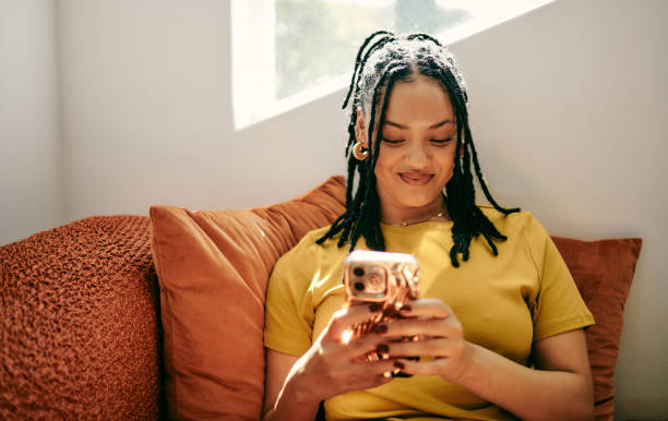 istock Modern Connectivity: Young Woman Engaged in Texting on Couch with Smartphone 2153803313