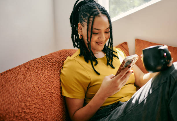 istock Young Woman Relaxing on Couch with Mobile Phone and Coffee 2153803314