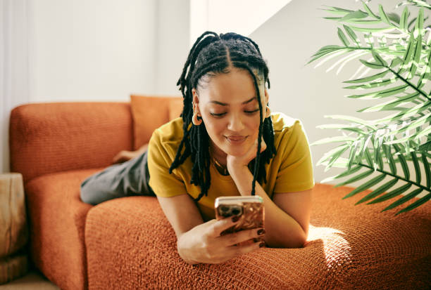 istock Modern Lifestyle: Young Woman Relaxing on Couch Texting on Smartphone 2153803341