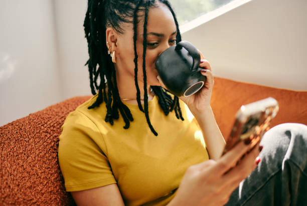 istock Young Woman Relaxing on Couch with Mobile Phone and Coffee 2153803361