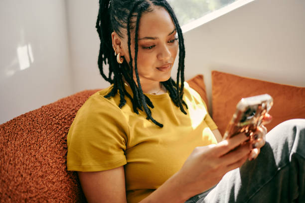 istock Modern Connectivity: Young Woman Engaged in Texting on Couch with Smartphone 2153803402