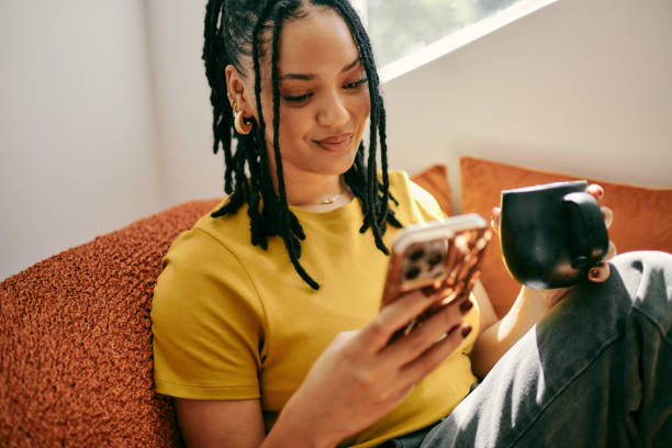 Young Woman Relaxing on Couch with Mobile Phone and Coffee