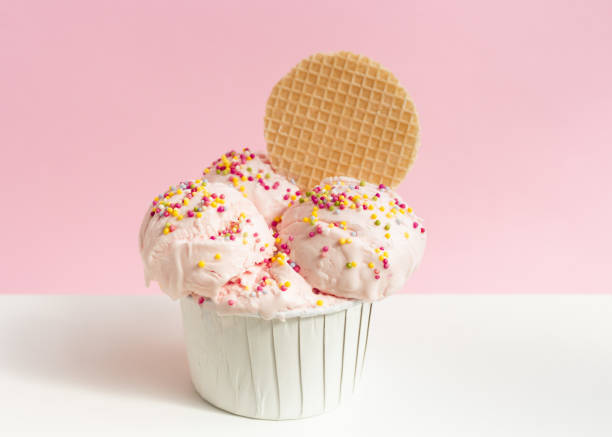 Ice cream balls decorated with colorful sprinkles and wafer in a paper cup on a pink background. Summer concept. Copy space. Ice cream balls decorated with colorful sprinkles and wafer in a paper cup, on a pink background. Summer concept. Copy space. ice-cream-pack stock pictures, royalty-free photos & images
