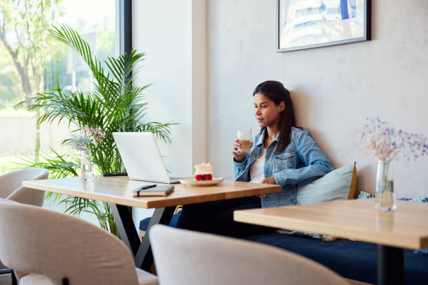 istock Relaxed woman drinking coffee using laptop at cafe 2153806721