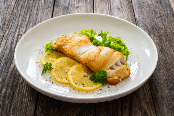 istock Fried halibut steak and fresh vegetables on wooden table 2153807314