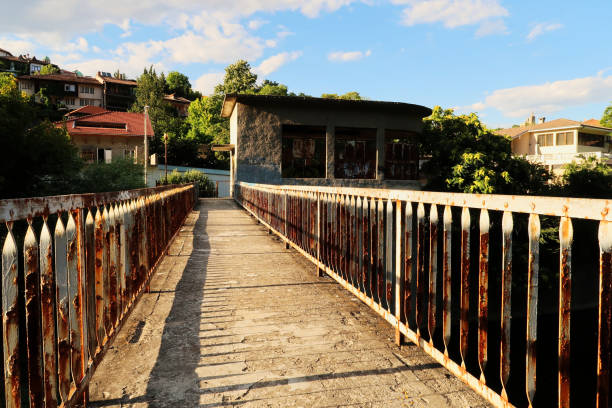 Walking over an abandoned dam on the Yantra River, rusted, rusty railings, handrails, rails on both sides of the concrete bridge, Veliko Tarnovo, Bulgaria 2022