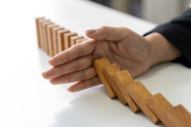 istock Hand stopping falling dominoes. Finance or failure concept. 2153810857