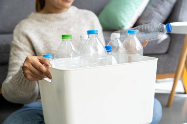 istock Asian woman collecting and separating recyclable garbage plastic bottles into a trash bin at home 2153811039