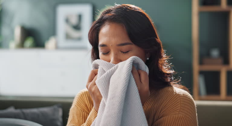 Couch, smell laundry and happy woman with clean blanket for detergent results, wellness and cleaning service. Female cleaner, smelling fabric and smile in apartment with soft cotton and fresh linen
