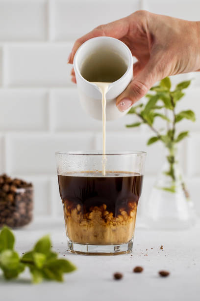 Refreshing glass of black coffee with a light foam, set against a modern white kitchen background