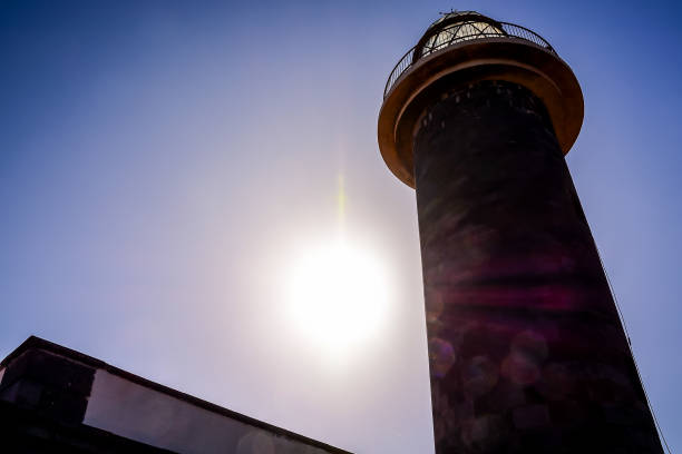 A lighthouse is in the background with the sun shining on it