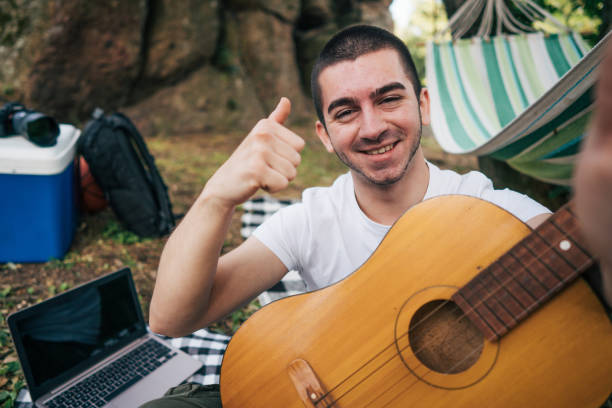 Young man resting on picnic blanket and making selfie