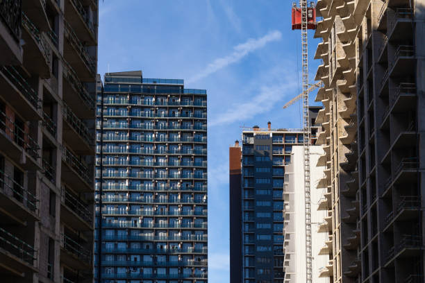 Residential multi-storey buildings and high-rise buildings under construction with a construction crane in the foreground on a sunny day. Concept of construction, urbanization