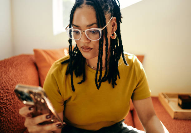 istock Modern Connectivity: Young Woman Engaged in Texting on Couch with Smartphone 2153830044