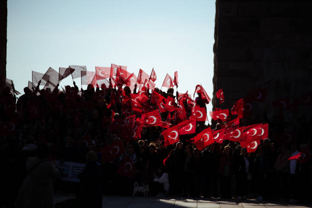 Canakkale, Turkey - Mar 18 2024: Photo of people holding Turkish flags at the location of the Martyrs' Memorial in Seddulbahir village, celebrating the 18 March Canakkale Victory.