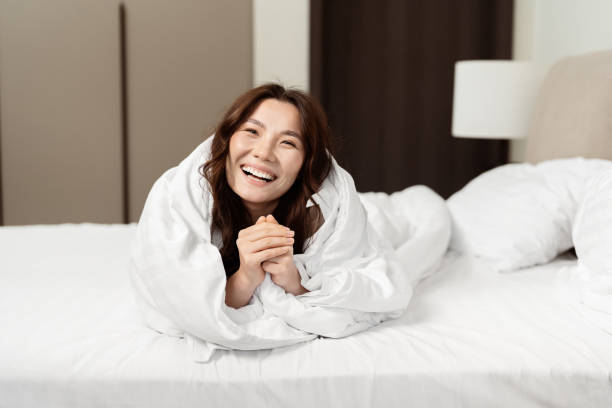 istock Happy Asian Woman Relaxing In Bed With White Sheets 2153835393
