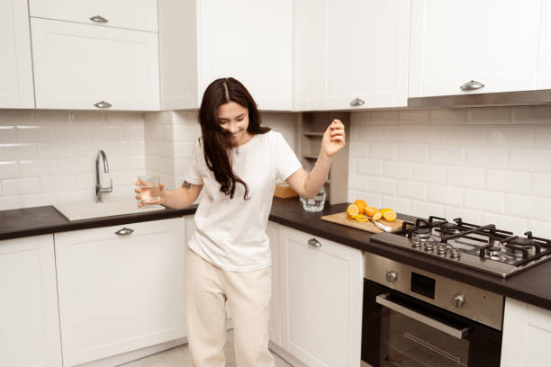 istock Young Woman Enjoying Fresh Lemon Water In Modern Kitchen 2153835531