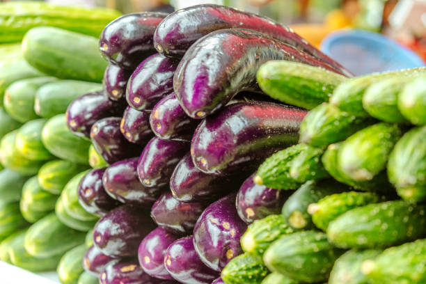 Close-up of fresh eggplants and cucumbers on display at a vibrant Hong Kong market. Perfect for concepts related to fresh produce, markets, and healthy eating.
