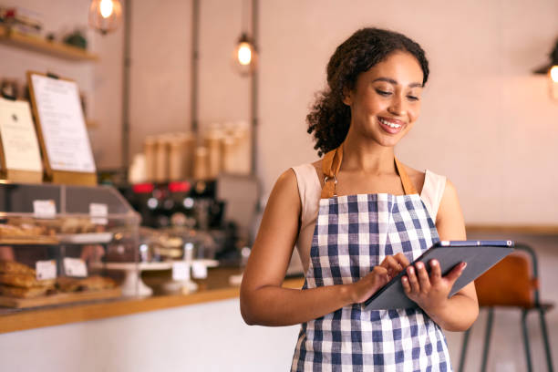 istock Young Woman Using Digital Tablet Wearing Apron Working In Coffee Shop Or Cafe 2153843179