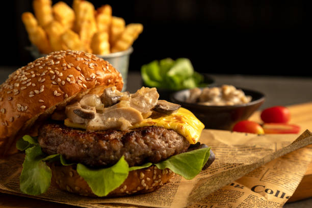 On rustic background, close-up reveals gourmet cheeseburger topped with mushrooms and lettuce, served with side of crispy fries
