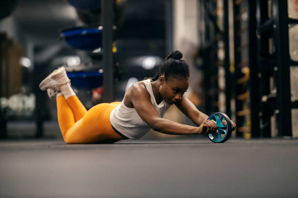 istock A dedicated fit black sportswoman doing workouts with ab roller at gym. 2153845610