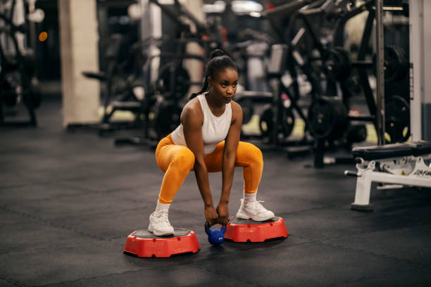 istock A strong black sportswoman doing deep squats with kettlebell at gym. 2153845640