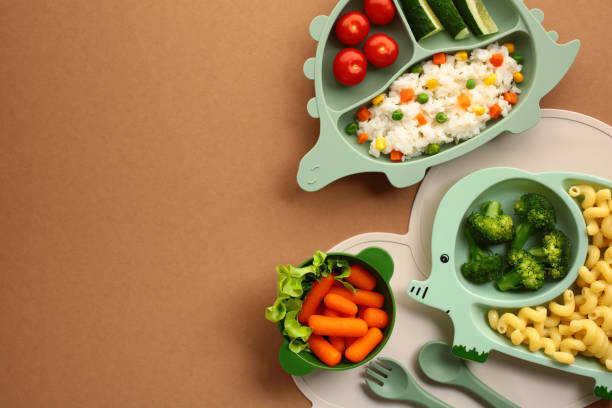 istock Kid-Friendly Healthy Meals. Nutritious meals served on animal-shaped plates. Features a dinosaur plate with tomatoes, cucumbers, and rice, a elephant plate with broccoli and pasta, and bowl of carrots 2153849903