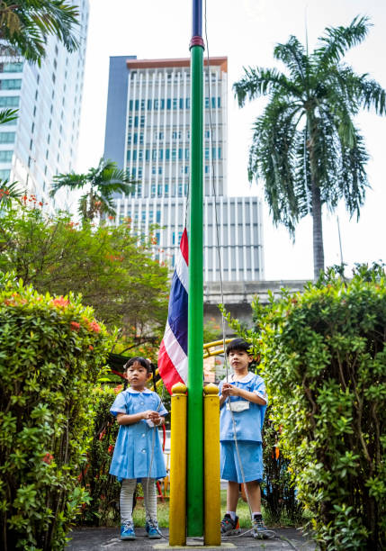 istock Two kindergarten students hoisting Thailand flag 2153851186