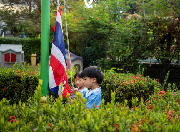 Kindergarten students hoisting Thailand flag in the school garden