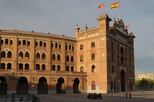 Closeup of exterior brick walls with pillars and arched windows, neo Mudejar style Las Ventas bullring, hanging lamps, sunny day in Madrid, Spain