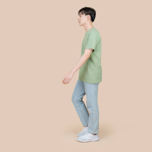 istock Young man walking in profile on beige background 2153857560