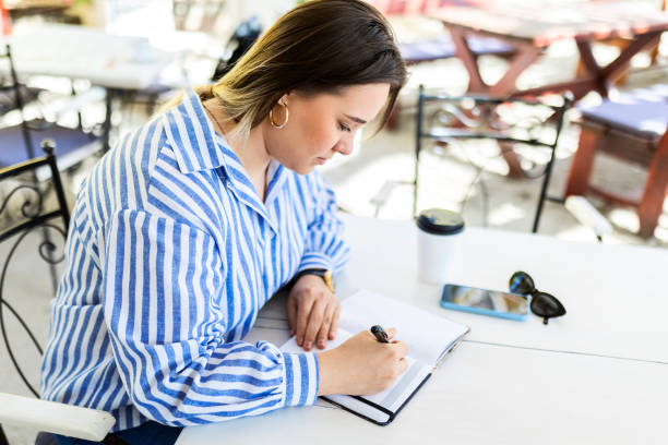 istock Young Woman Writing in Notebook Outdoors 2153860965