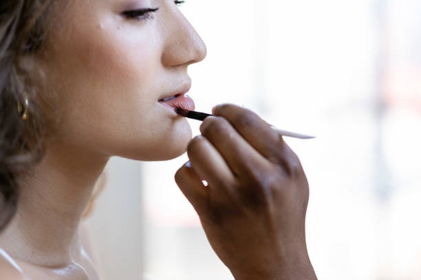 istock Makeup artist applying lip color to models face using small brush. 2153861958