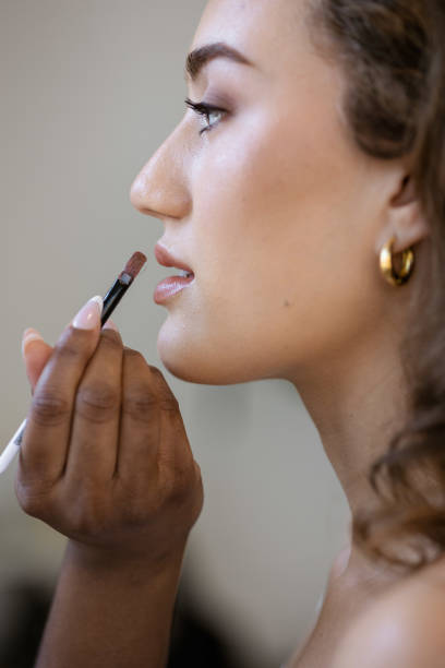 istock Makeup artist applying lipstick to model 2153861969
