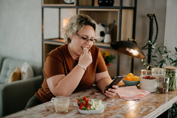 istock Woman is eating fruit and using a mobile phone 2153868100