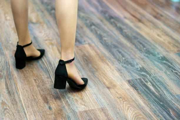 Women's feet in suede shoes on a laminated floor