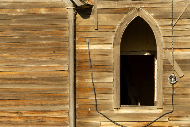 A close up of a window of the abandoned Milk River Valley Church with an old power source and cord