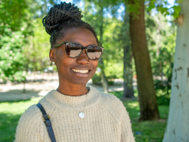 istock a young woman smiling with sunglasses in a park 2153876870