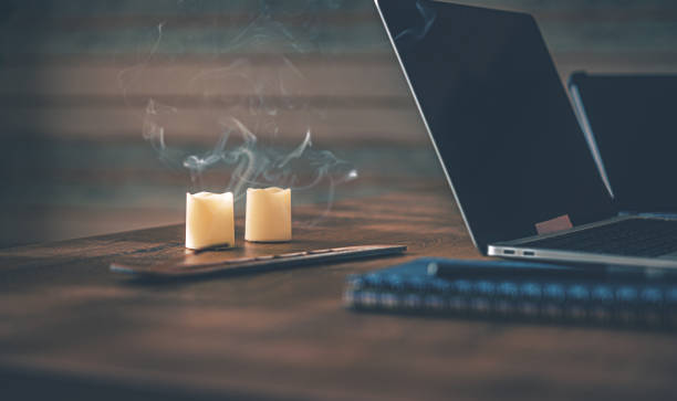 istock Home Office. On the table there is a laptop, a tablet, a blue notebook with a pen for notes, two candles and an incense stick 2153878664