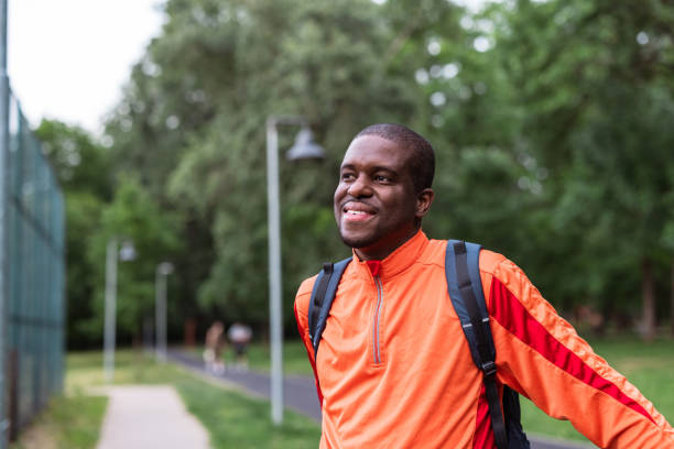 istock Man smiling outdoors in sport orange jacket with backpack 2153880749