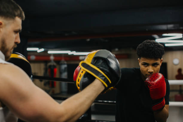 istock A young boxer practices punches with a trainer in a boxing studio. 2153881414