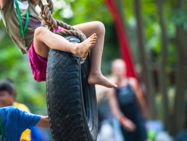 Children are playing in the park, swinging on a car tire swing